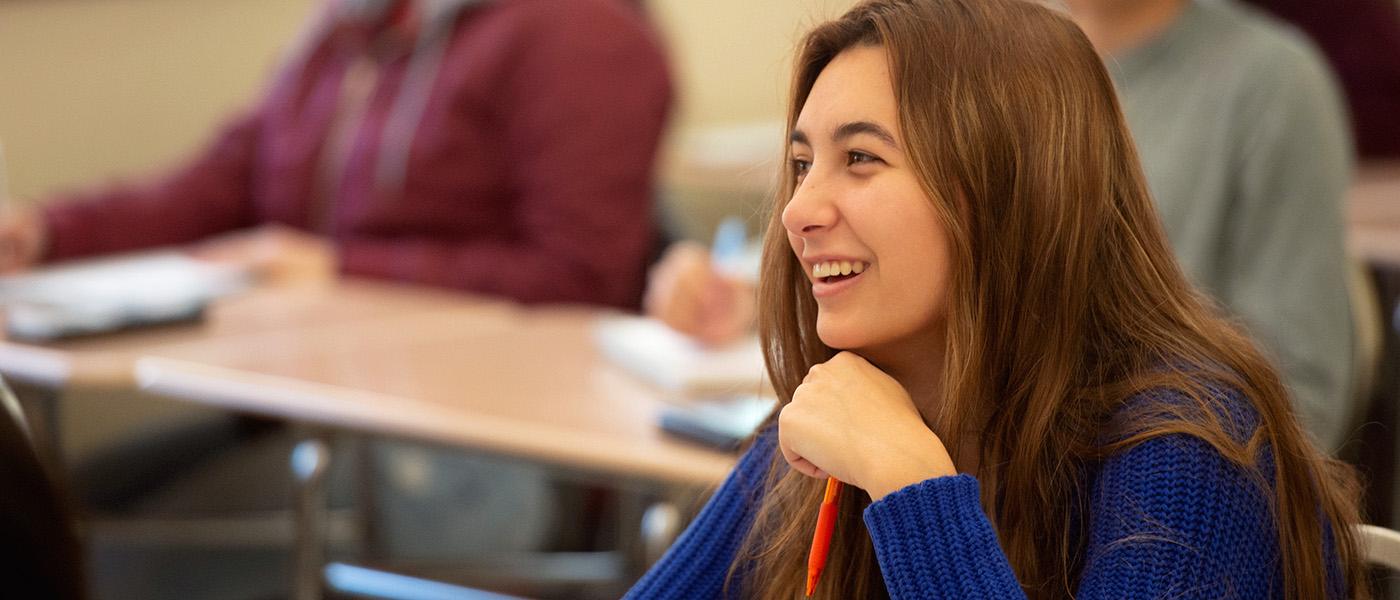 Female math student in her desk, smiling during class.